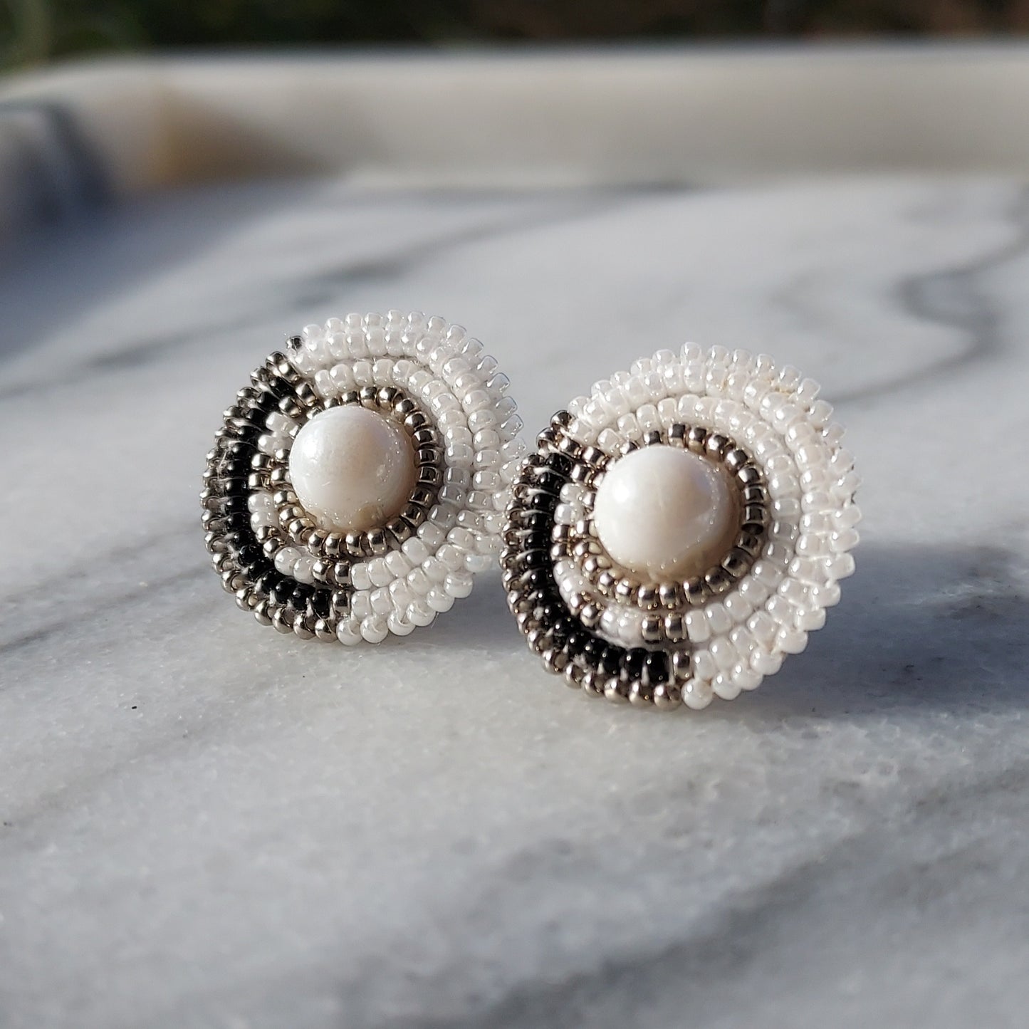 Cheyanne Symone’s Little Ash Earrings Sitting in a Marble Tray | Black and White Glass Seed Bead Earrings Featuring Metal Plated Beads Wrapped Around a Glass Bead Center