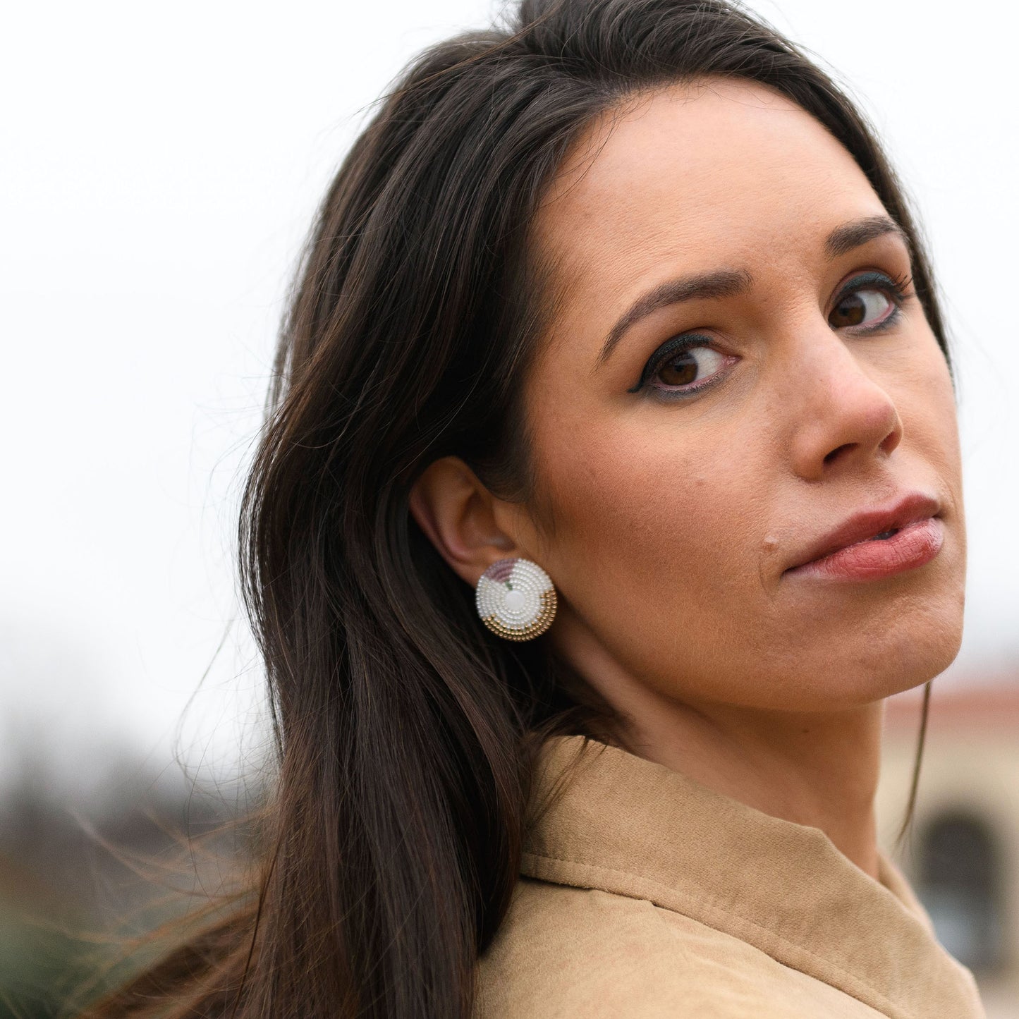 Model Chelsea Hicks looking over her shoulder and wearing Cheyanne Symone’s beaded “In Bloom” Statement Earrings. The earrings are white with a small gold beaded base representing the soil and pink at the top representing a blooming tulip.