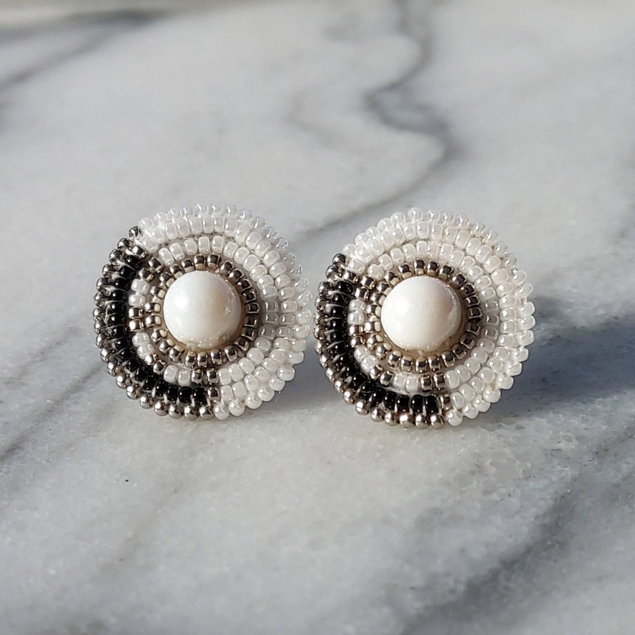 Cheyanne Symone’s Little Ash Earrings Sitting in a Marble Tray | Black and White Glass Seed Bead Earrings Featuring Metal Plated Beads Wrapped Around a Glass Bead Center