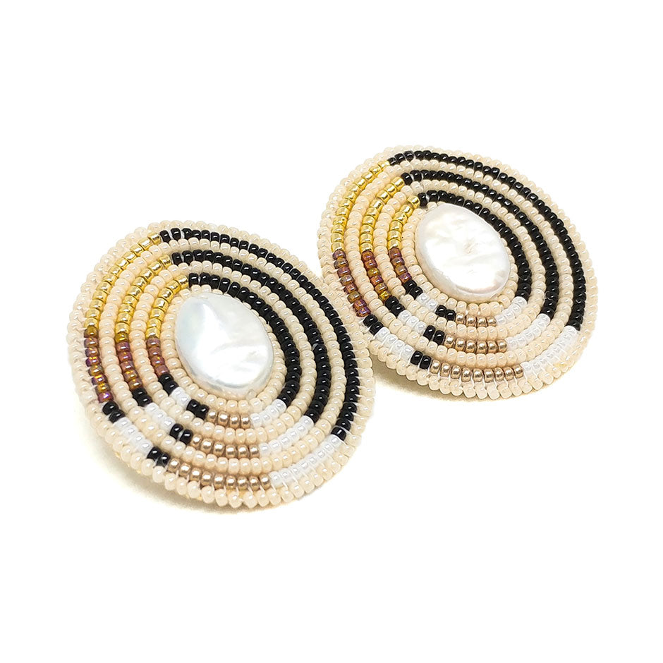 Close-up of Cheyanne Symone’s Oval Direction Statement Earrings | Ivory, Black, Gold, and White Glass Seed Beads Wrapped Around an Oval Shaped Freshwater Pearl Center 
